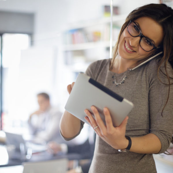 How to Become a Great Personal Assistant (PA or EA) - Businesswoman talking on phone and uses digital tablet