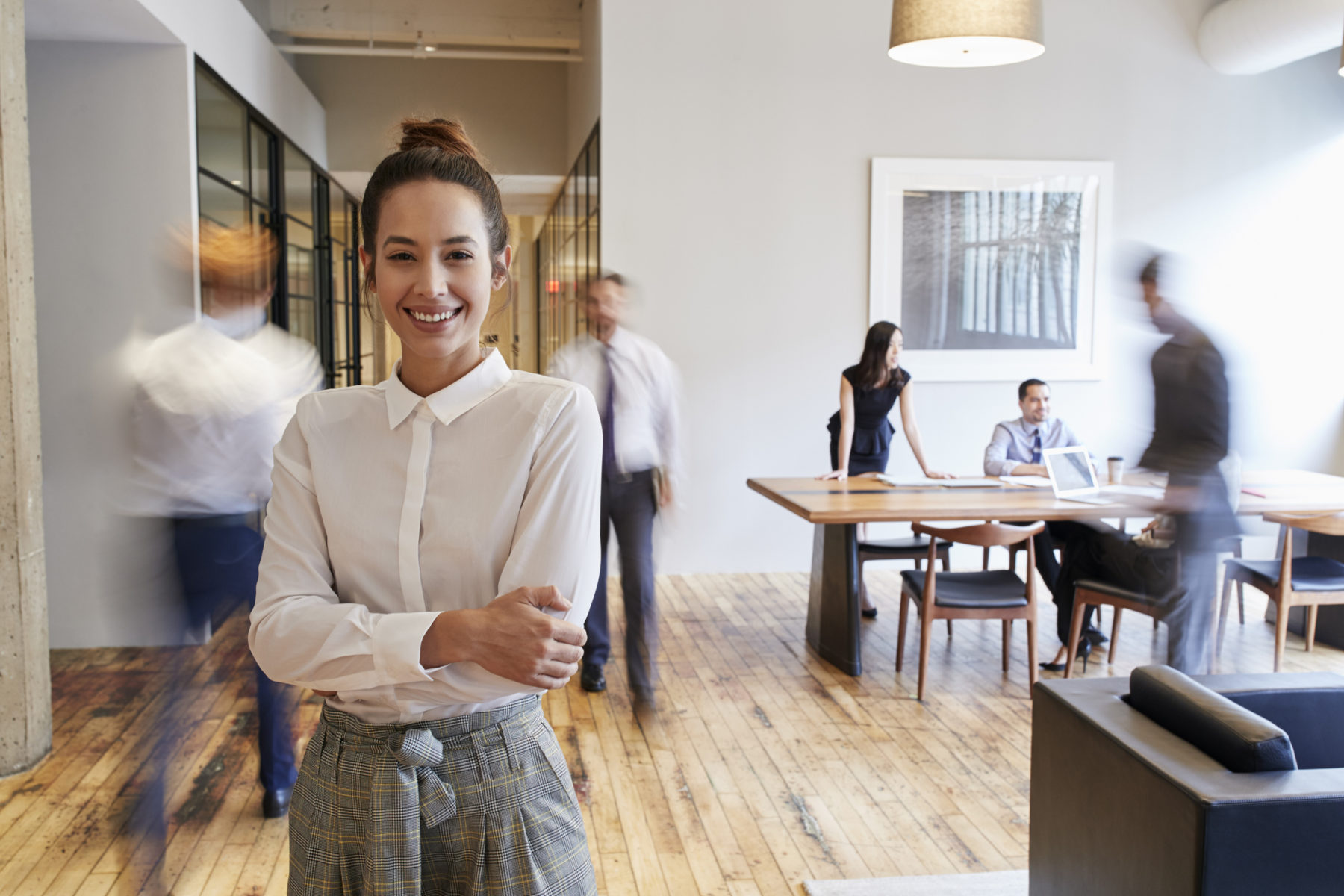 Portrait of young woman in a busy modern workplace - representing how to be happy at work concept